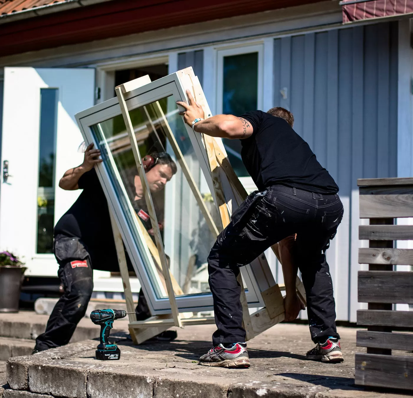 två killar ställer ner ett fönster